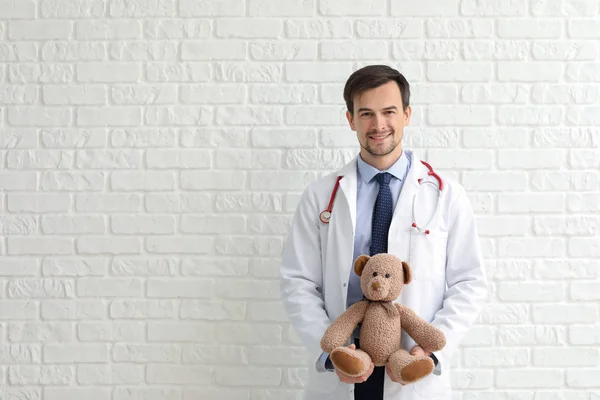 Kinderarts Met Speelgoed Dragen Tegen Witte Bakstenen Muur — Stockfoto