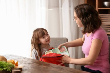 Sevimli kızı evde sırt çantasına beslenme çantası ambalaj ile anne