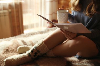 Güzel kadın evde içme sıcak kakao ve kitap okumak
