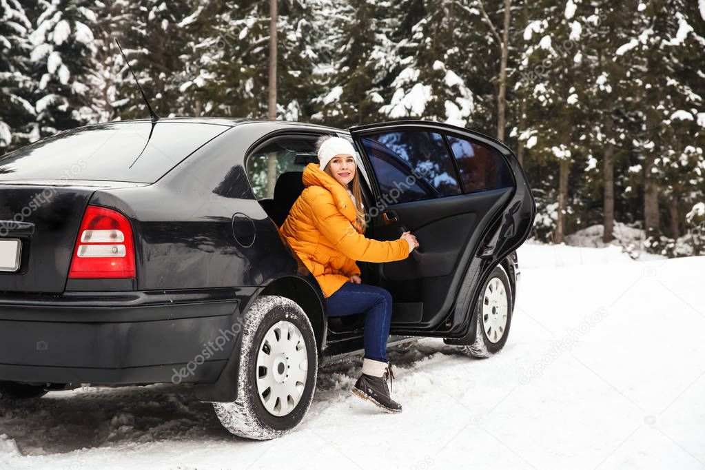 Young woman getting out of car at snowy winter resort