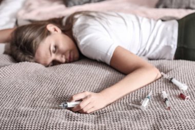 Bilinçsiz olan kadın yatakta yatarken şırınga. İntihar kavramı