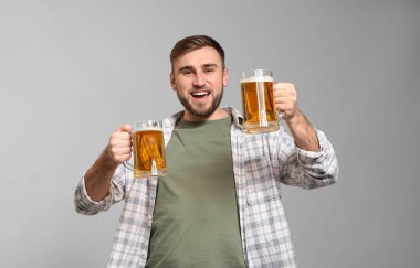 Gri arka plan üzerinde bira kupaları ile yakışıklı genç adam. Aziz Patrick günü kutlama