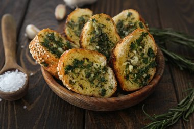 Lezzetli bir kase sarımsaklı ekmek ahşap masanın üstüne kesmek