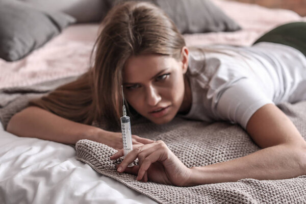 Young woman with syringe is going to commit suicide at home