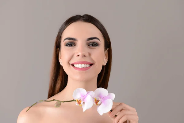 Schöne Junge Frau Mit Orchideenblüten Auf Farbigem Hintergrund — Stockfoto