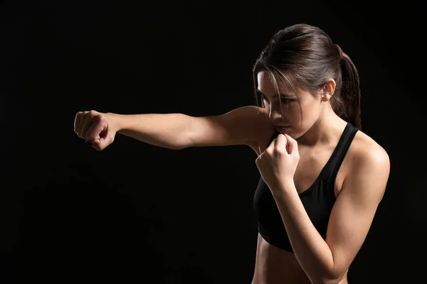 Sporty female boxer on dark background