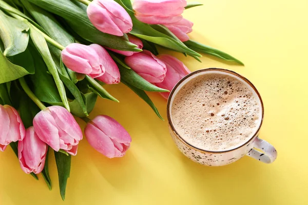 Bouquet of beautiful tulips and cup of coffee on color background