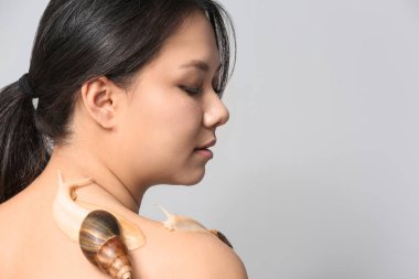 Asyalı kadın ile dev Achatina salyangoz ışık arka plan üzerinde