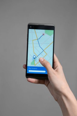 Cep telefonu ekran gri arka plan üzerinde yol ile harita görüntüleme tutan kadın