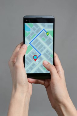 Cep telefonu ekran gri arka plan üzerinde yol ile harita görüntüleme tutan kadın