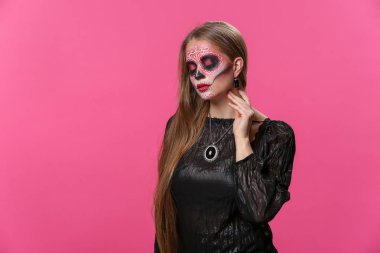 Meksika Ölüler Günü için yüzünde boyalı kafatası olan genç bir kadın.