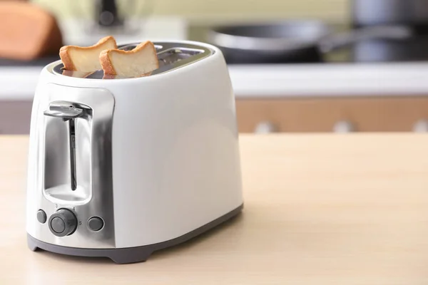Toaster with bread slices on table