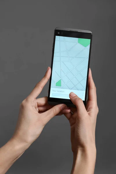 Žena Držící Mobilní Telefon Zobrazení Mapy Obrazovce Šedé Pozadí — Stock fotografie