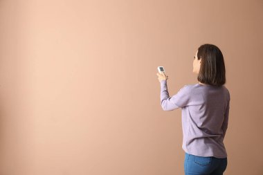 Renk arkaplanı üzerinde klima uzaktan kumandalı genç kadın