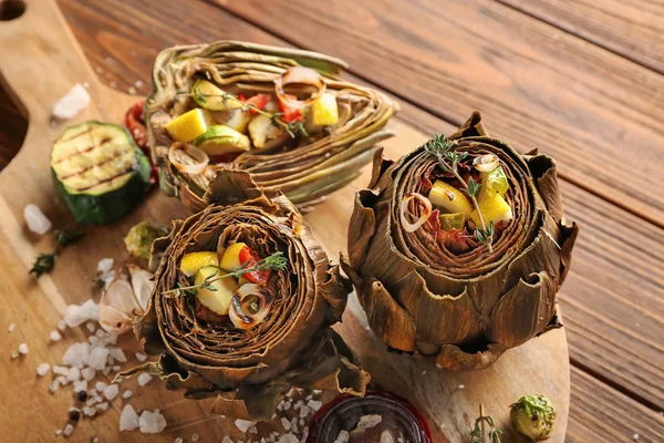 Board with tasty artichokes and vegetables on table, closeup — Stock Photo, Image