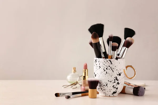 Conjunto de pinceles de maquillaje y cosméticos sobre mesa —  Fotos de Stock