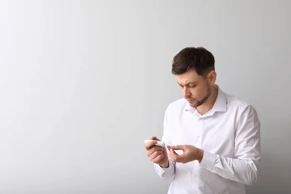 Diabetische man met digitale glucometer op lichte achtergrond — Stockfoto