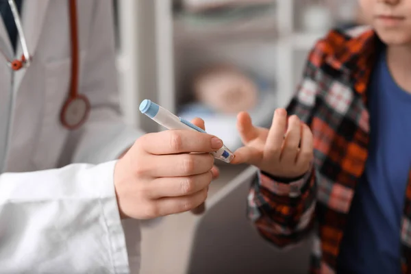 Lékař odběr krve diabetického dítěte v klinice — Stock fotografie