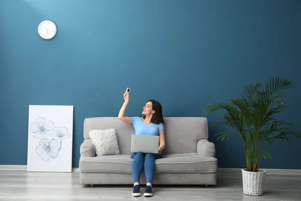 Young woman switching on air conditioner at home — Stock Photo, Image