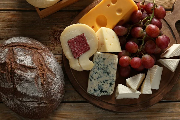 Fából készült fedélzet-val ízletes sajt és a kenyér az asztalon — Stock Fotó