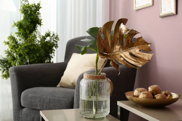 Tropical leaves and plate with golden apples in interior of room — Stock Photo, Image