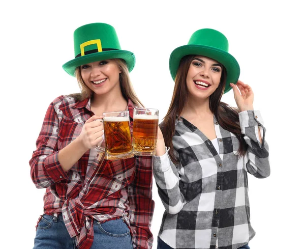 Hermosas mujeres jóvenes con sombreros verdes y tazas de cerveza sobre fondo blanco. Celebración del Día de San Patricio — Foto de Stock