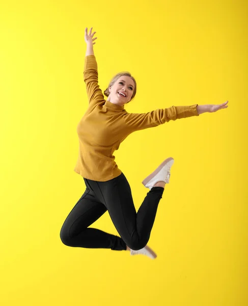 Jumping young woman on color background — Stock Photo, Image