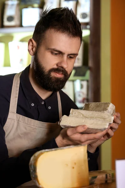 Vendedor masculino com delicioso queijo na loja — Fotografia de Stock