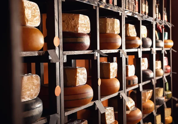 Assortment of tasty cheese on shelves in store