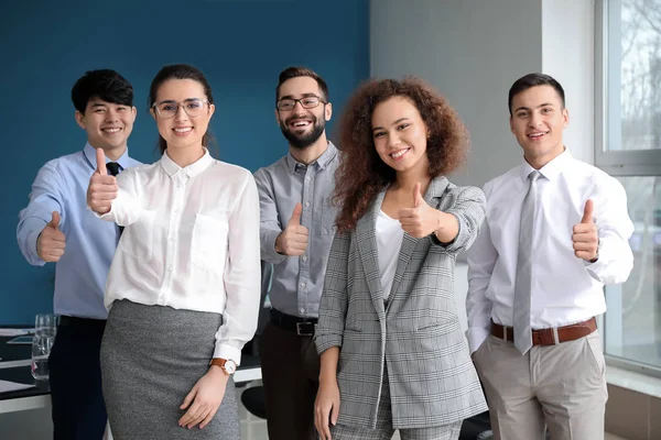 Team of young business people showing thumb-up gesture in office — Stock Photo, Image
