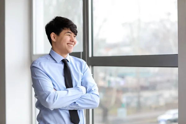 Portrait of young Asian businessman near window in office — Stock Photo, Image