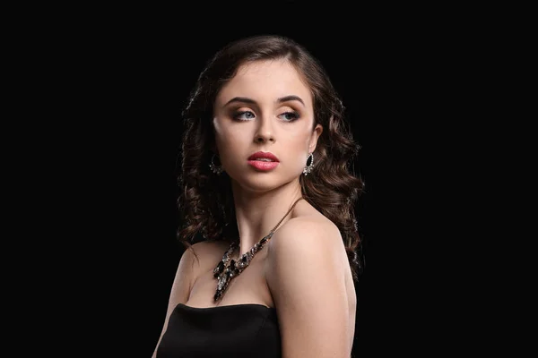 Giovane donna con bellissimi gioielli su sfondo scuro — Foto Stock