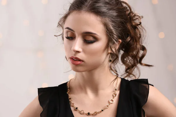 Mujer joven con hermosas joyas contra luces desenfocadas —  Fotos de Stock