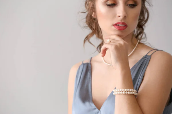 Young woman with beautiful pearl jewelry on light background — Stock Photo, Image