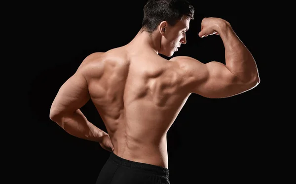 Muscular bodybuilder on dark background, back view — Stock Photo, Image