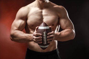 Koyu arka plan üzerinde rugby topu ile kas vücut geliştirmeci