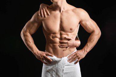 Kaslı seksi vücut geliştirmeci koyu arka plan üzerinde eller ile