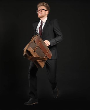 Şık çanta ile işadamı koyu arka plan üzerinde atlama