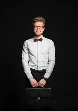 Koyu arka plan üzerinde şık evrak çantası ile yakışıklı işadamı