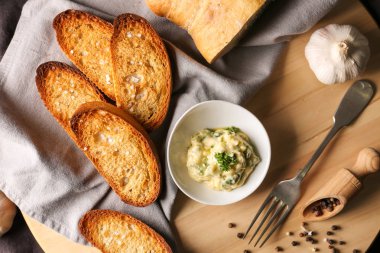 Dilimlenmiş ekmek ve ahşap tahta üzerinde yayılan sarımsak