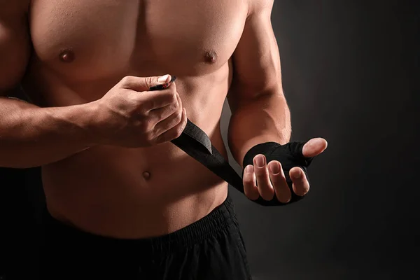 Attraktive Sportler wickeln Armband vor dunklem Hintergrund — Stockfoto