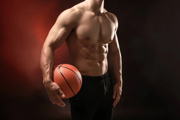 Muskulöser Bodybuilder mit Ball auf dunklem Hintergrund — Stockfoto