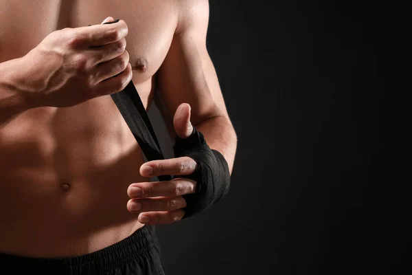 Attraktive Sportler wickeln Armband vor dunklem Hintergrund — Stockfoto