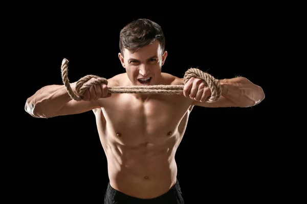 Muskulöser Bodybuilder mit Seil auf dunklem Hintergrund — Stockfoto