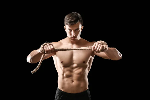 Muscular bodybuilder with rope on dark background — Stock Photo, Image