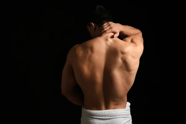 Muscular sexy bodybuilder with towel on dark background, back view — Stock Photo, Image