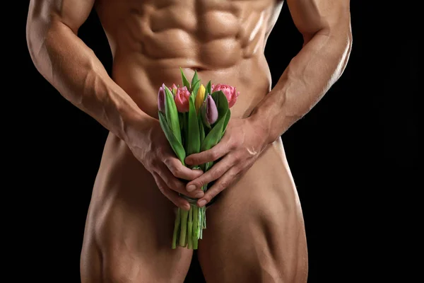 Muskulös sexig bodybuilder med bukett blommor på mörk bakgrund — Stockfoto