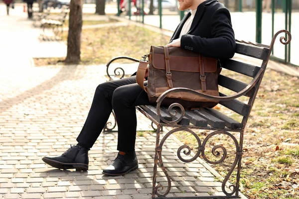 Handsome businessman with stylish briefcase in city park