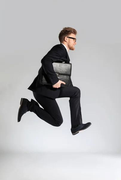 Hombre de negocios saltando con un elegante maletín sobre fondo claro —  Fotos de Stock