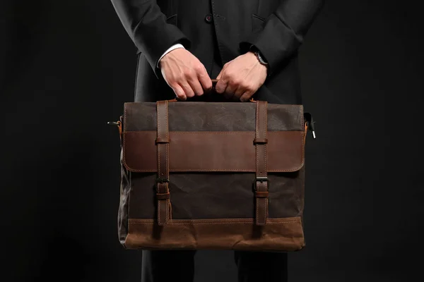 Handsome businessman with stylish briefcase on dark background